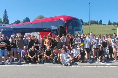 Il gruppo 2026 davanti al pullman rosso e al pulmino
